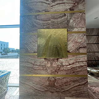 Sculpture Projects – Golden metal wall installation integrated into a marble wall within a luxury interior space in Morocco