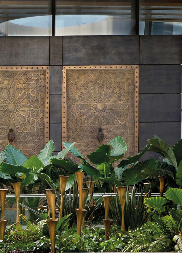 Panneaux muraux en bronze gravés de motifs géométriques marocains zellige dans un espace de luxe avec jardin intérieur, art mural sur mesure réalisé au Maroc
