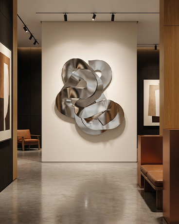 Sculpture murale métallique argentée installée dans une galerie d’art contemporaine au Maroc
