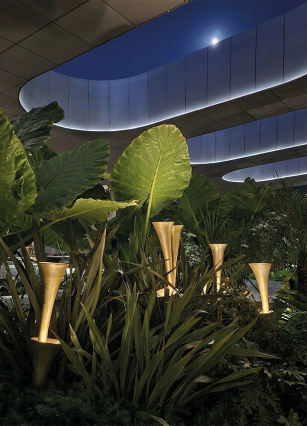 Sculptures lumineuses en forme de trompette en laiton doré intégrées dans un jardin tropical d'un espace de luxe, art paysager sur mesure réalisé au Maroc