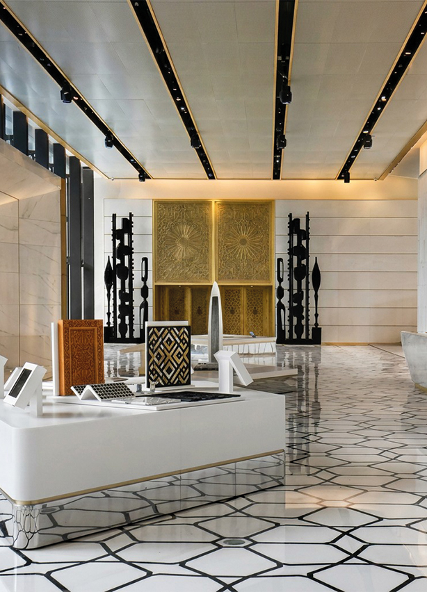 Sculptures totems verticales noires sculptées exposées dans le lobby d'un hôtel de luxe avec panneaux dorés et sol géométrique, art décoratif sur mesure au Maroc